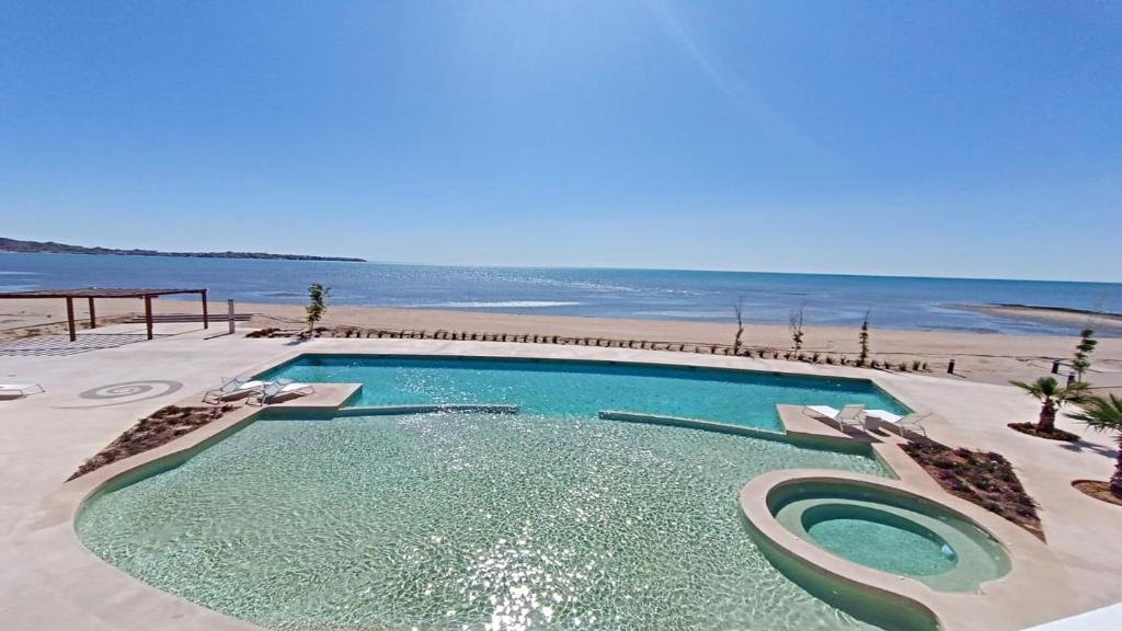 a swimming pool next to a beach with chairs at Costa Divina A2 by Kivoya in La Choya