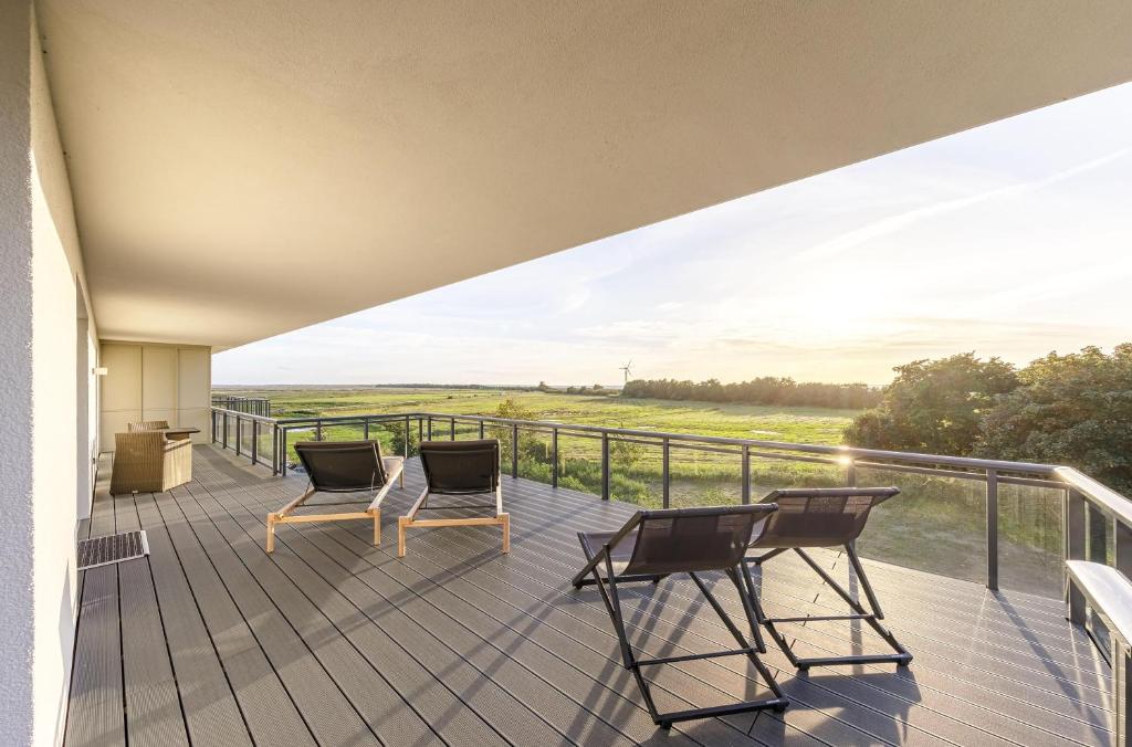 twee stoelen op een terras met uitzicht op een veld bij 5 Sterne Ferienwohnung Strandblick in Wustrow