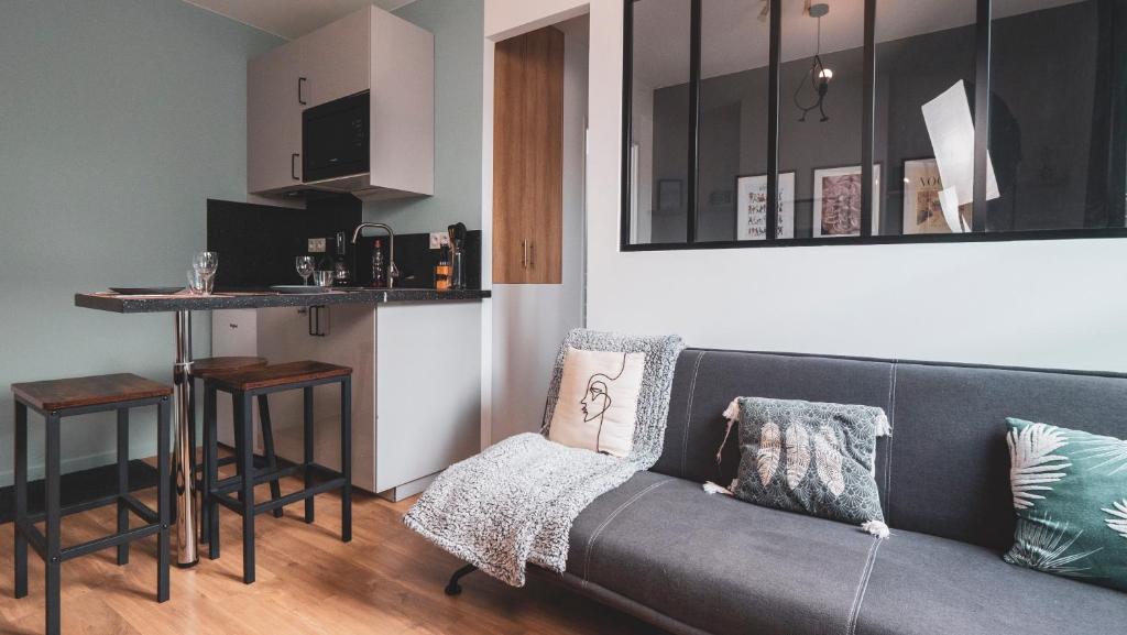 a living room with a couch and a kitchen at Le Douillet Cocon - Centre in Amboise