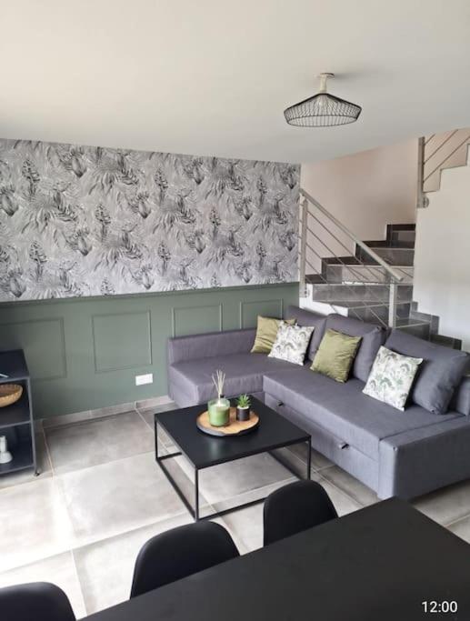 un salon avec un canapé violet et une table dans l'établissement MAISON NEUVE 15 min STRASBOURG, à Geudertheim