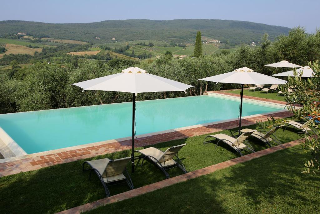 a swimming pool with chairs and umbrellas at Fattoria Abbazia Monte Oliveto in San Gimignano