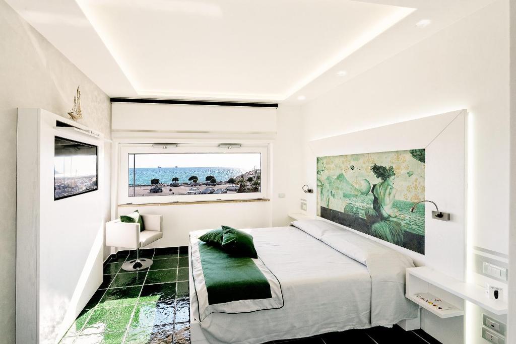 a white bedroom with a large bed and a window at La Madegra Seasuite in Salerno