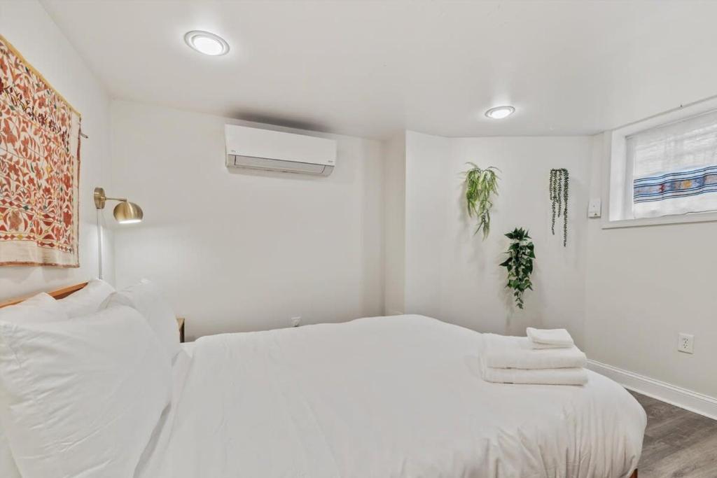 a white bedroom with two beds and a window at Garden-Level 2-BR Apt in Historic Petworth Home in Washington, D.C.