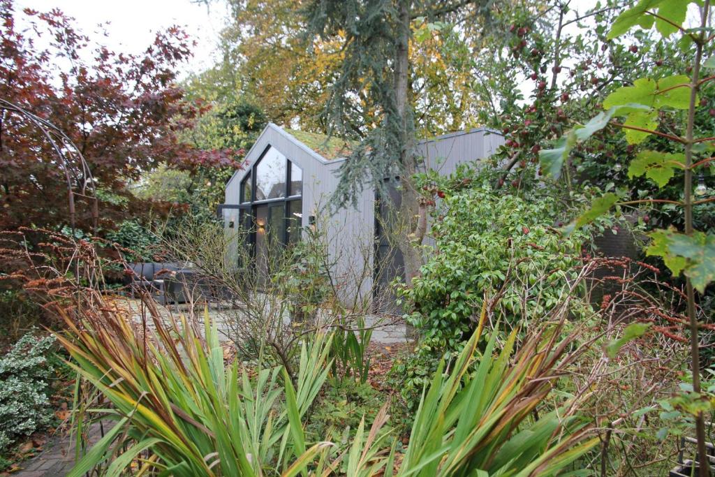 una casa de cristal en un jardín con plantas en De Bosuil, en Bergen