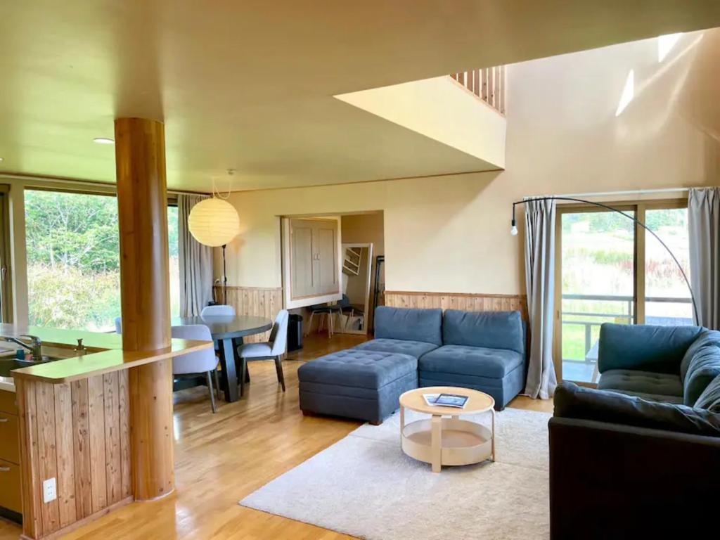 a living room with a blue couch and a table at Cottage with views of the Niseko mountain range - Mountain View Niseko in Niseko