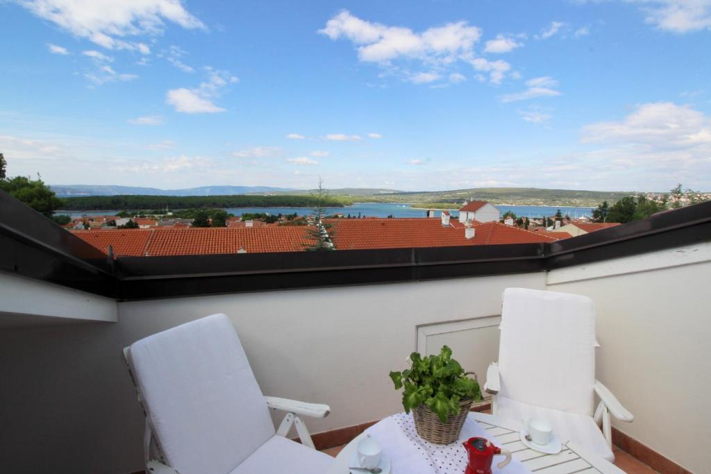 two white chairs and a table on a balcony with a view at Apartment Klepac in Punat