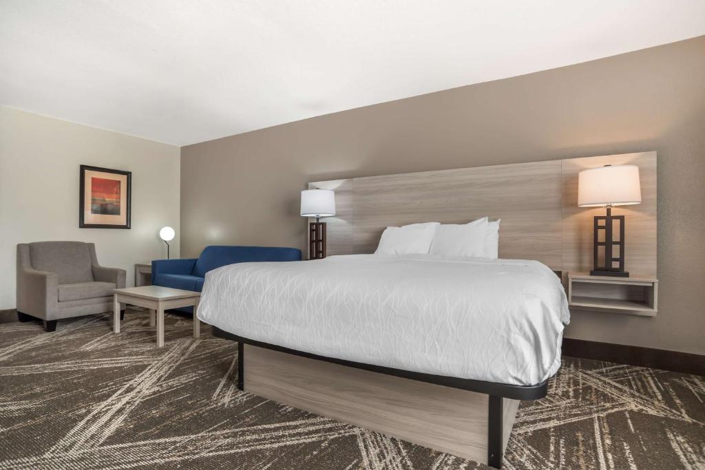 a hotel room with a large bed and a chair at Best Western Plus Jackson Downtown Coliseum in Jackson