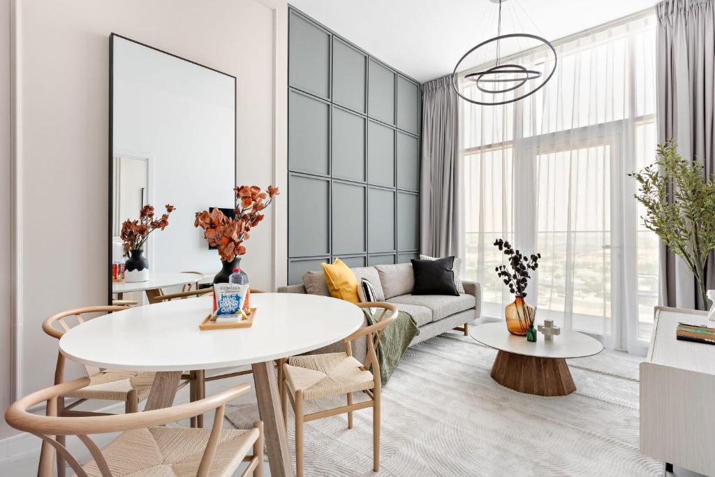 a living room with a table and chairs and a couch at Silkhaus Modern 1BDR in Oasis Near Masdar City Park in Yas Island