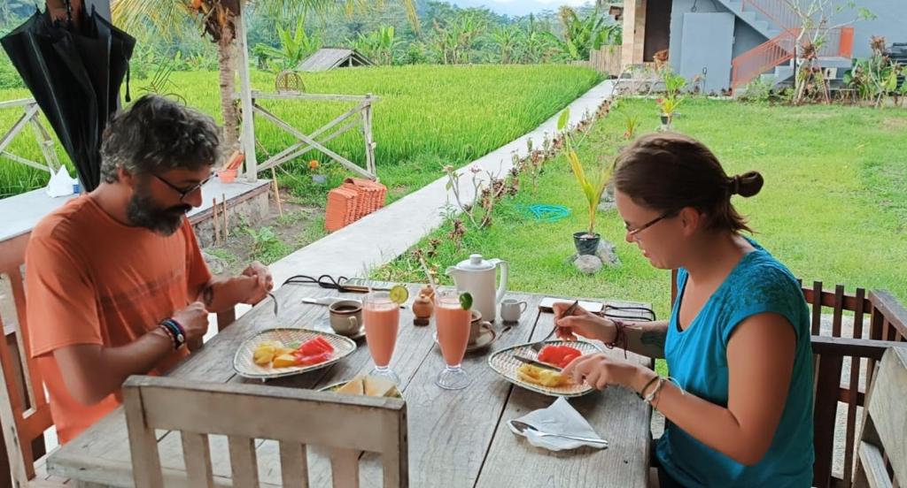 een man en een vrouw zitten aan een tafel en eten bij Tirta Unda Sidemen in Sidemen