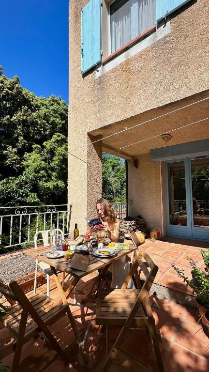 une femme assise à une table sur un patio dans l'établissement Le Vieux Moulin, Cotignac, à Cotignac