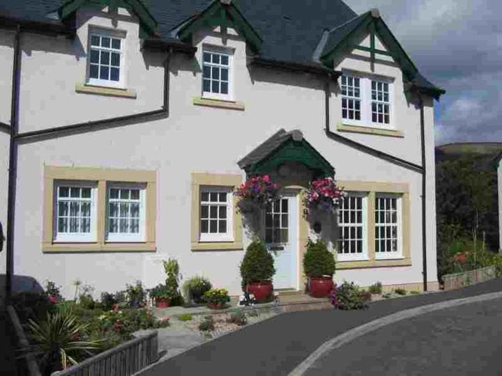 a white house with flowers in front of it at Tweed View B&B in Peebles