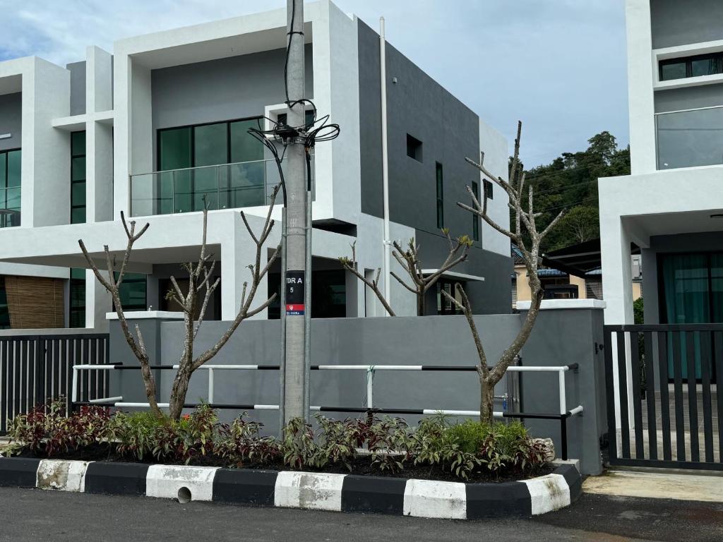 a white building with two trees in front of it at Ruma Langkawi in Kuah