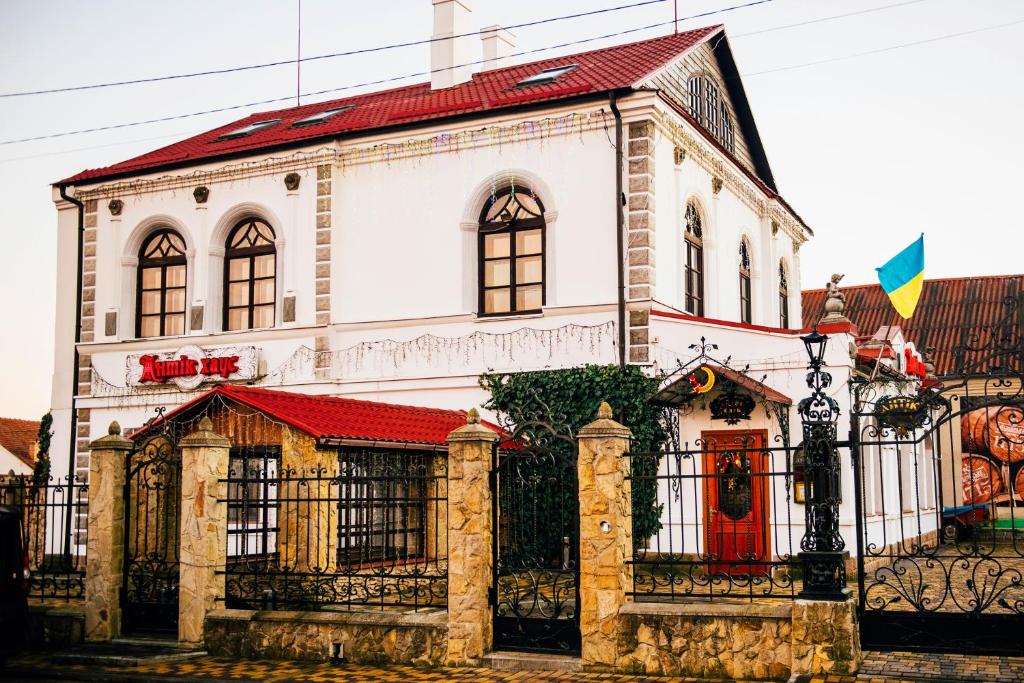 una casa blanca con una puerta roja y una valla en Antique House Hotel, en Dubno