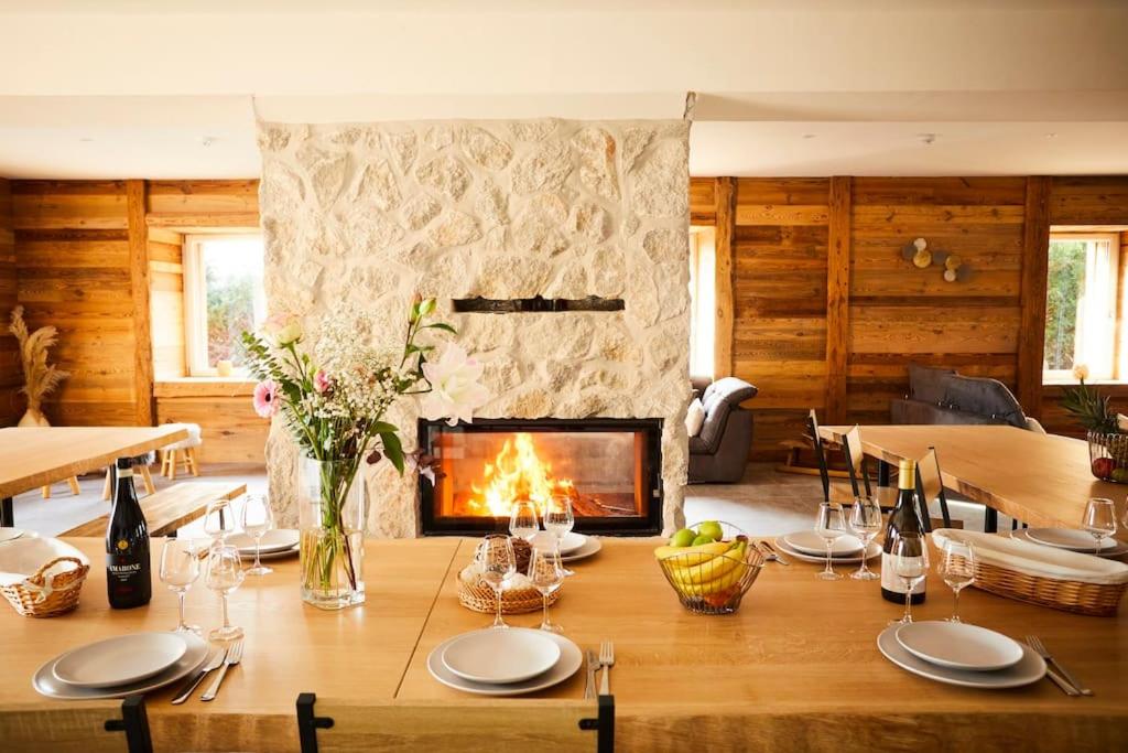 ein Esszimmer mit Tisch und Kamin in der Unterkunft chalet la forgerie Piscine Jacuzzi Cinéma in La Forge
