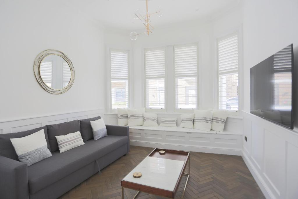 ein Wohnzimmer mit Sofa und Tisch in der Unterkunft Coachman's Cottage- Worthing Beach sleeps 9 in Worthing