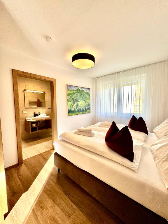 a bedroom with a large bed and a bathroom at Alpenstolz Damüls Haus 4 - Stilvoll urlauben in den Bergen in Damuls