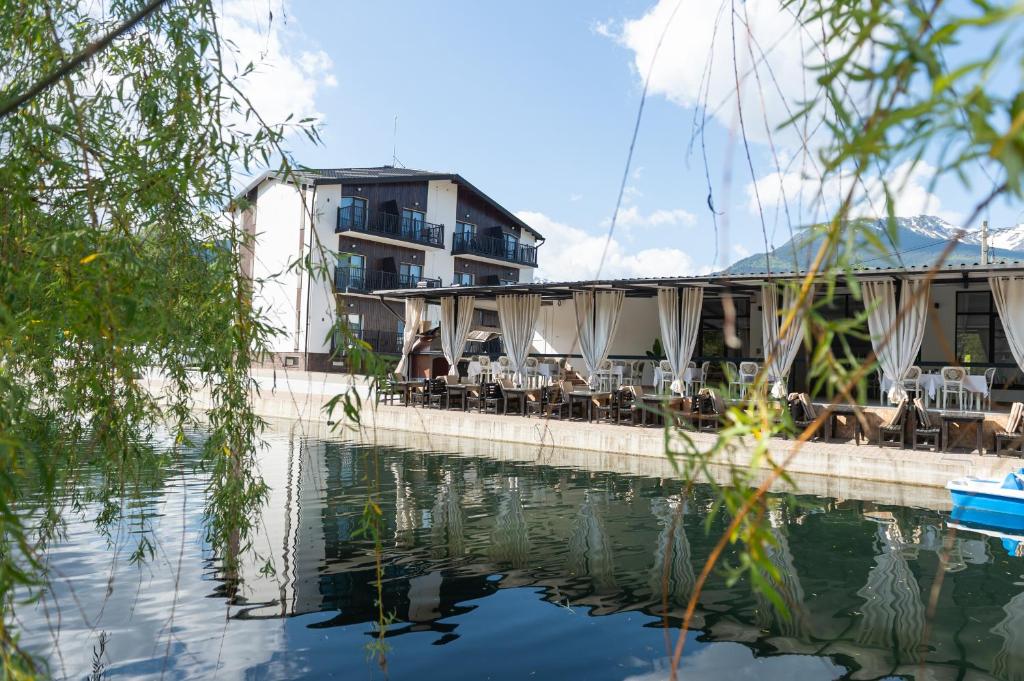 a building with tables and chairs next to the water at Complex Pescăresc Gura Repezii Borșa in Borşa