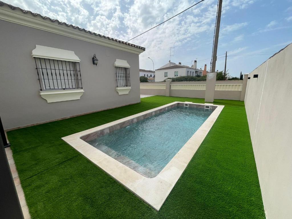un patio trasero con piscina y césped verde en Villa Bolet, en Chiclana de la Frontera