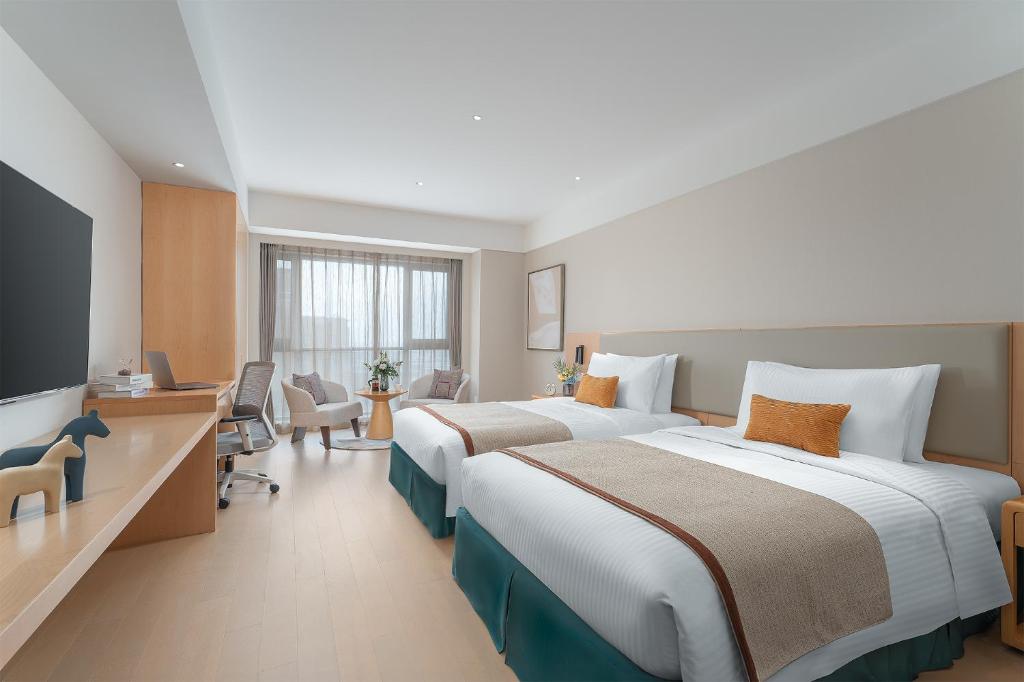pokój hotelowy z dwoma łóżkami i telewizorem w obiekcie Somerset Fengdong Xi'an w mieście Xianyang
