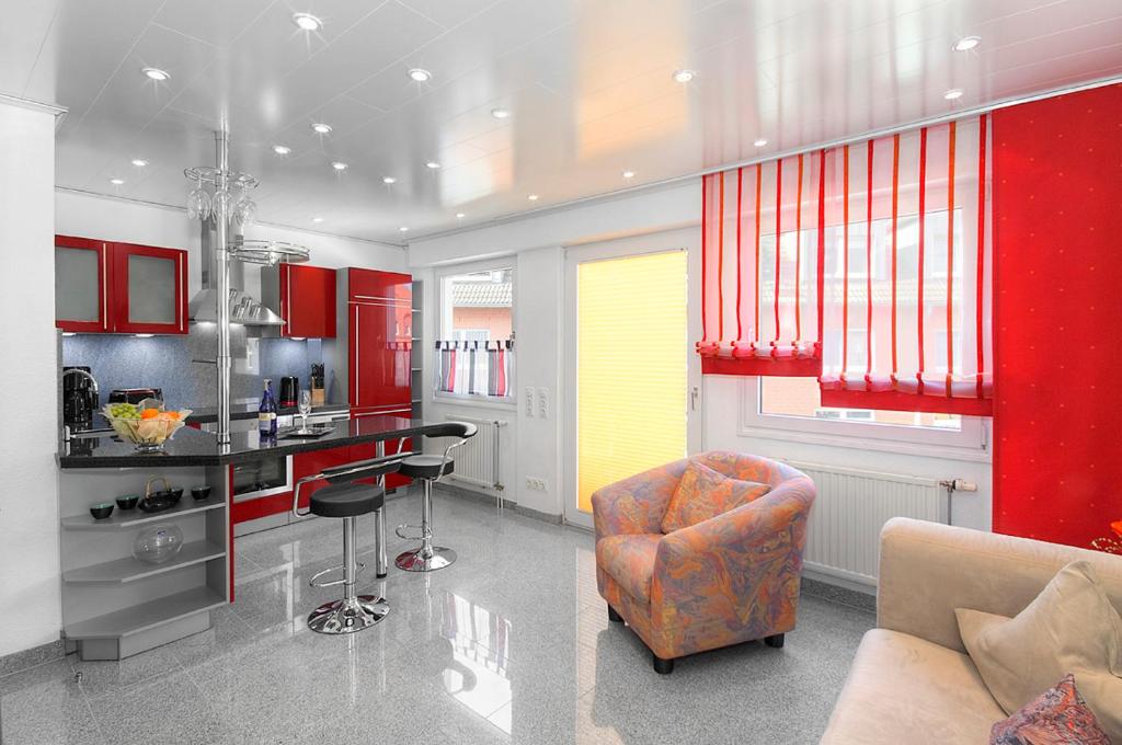 eine Küche mit roten Schränken, einem Sofa und einem Stuhl in der Unterkunft Appartements DW16~17~19 in Dortmund in Dortmund