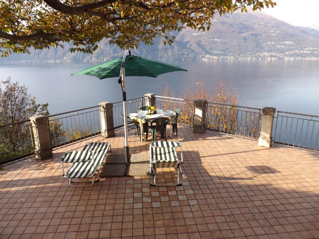 Una mesa y dos sillas y una sombrilla en un patio. en Exclusive Villa Crotto Lake View, en Varenna