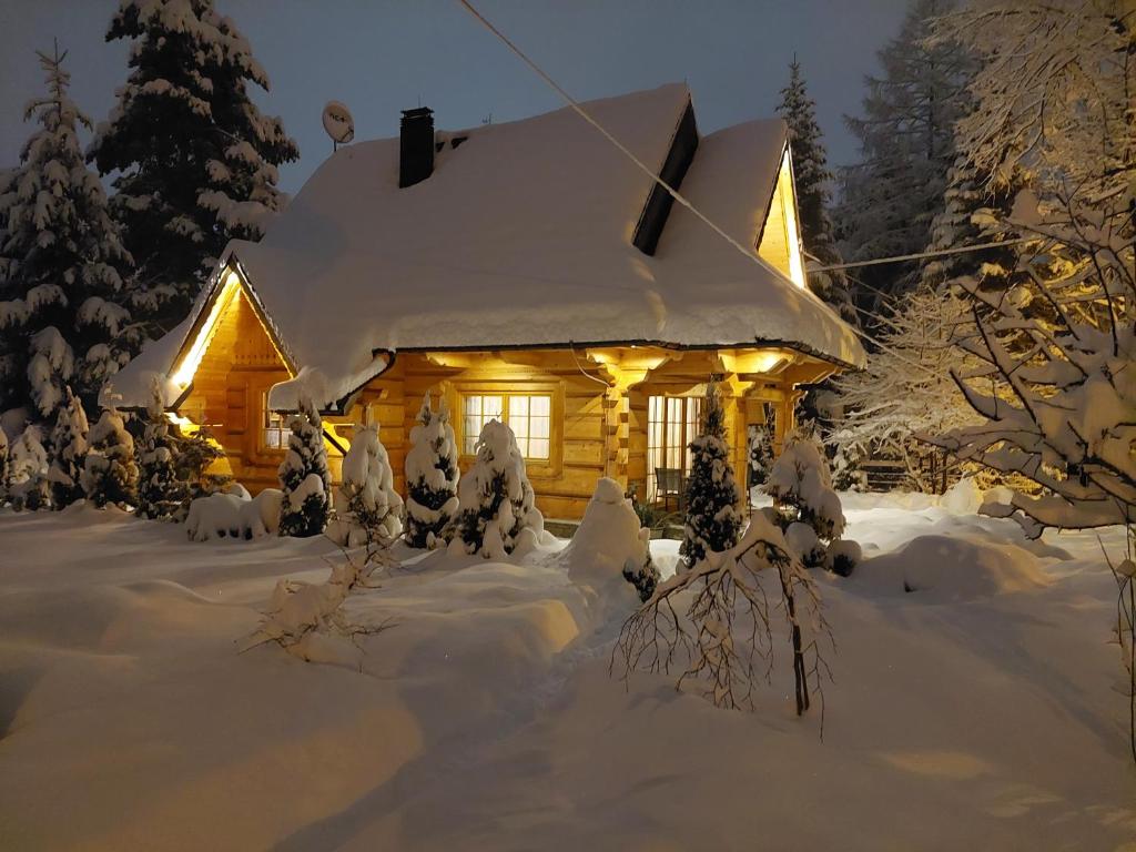 a cabin covered in snow with lights on it at BIAŁY PUCH in Zakopane