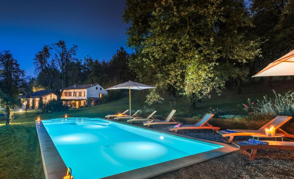 une piscine avec des chaises longues et un parasol dans l'établissement CASCINA MONFERRATO 12, Emma Villas, à Sala Monferrato