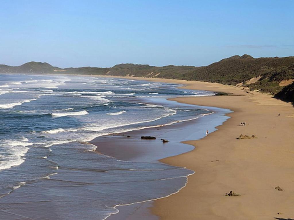 una spiaggia con persone che camminano sulla sabbia e sulle onde di Brenton Breakers a Brenton-on-Sea
