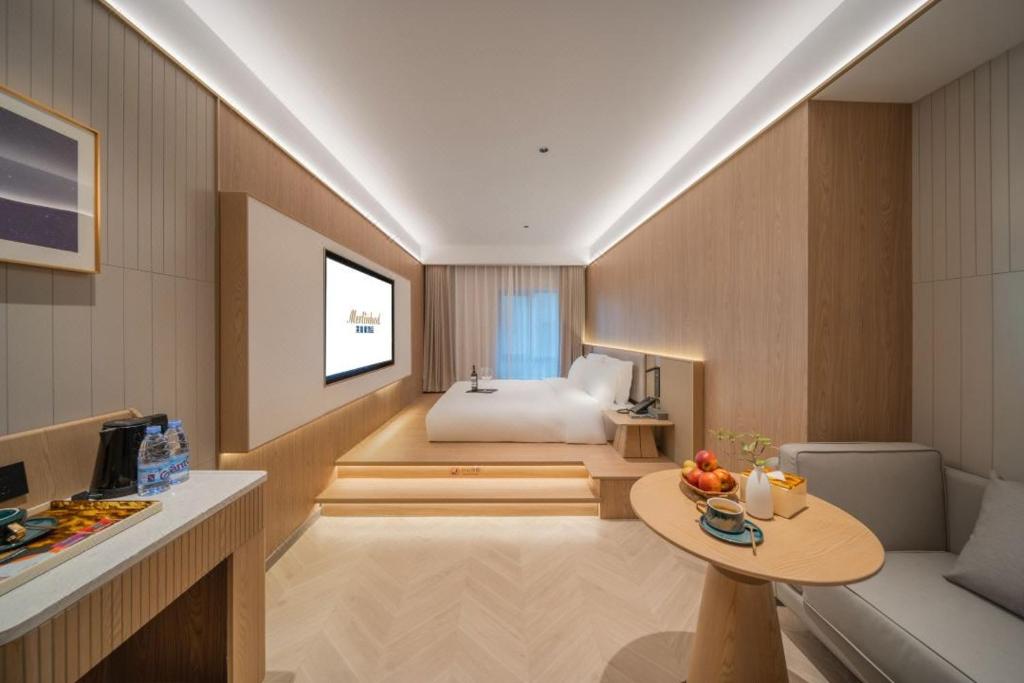 una camera da letto con un letto e un tavolo in una stanza di Merlinhood Hotel Xi'an Bell and Drum Tower Changlemen Subway Station a Xi'an