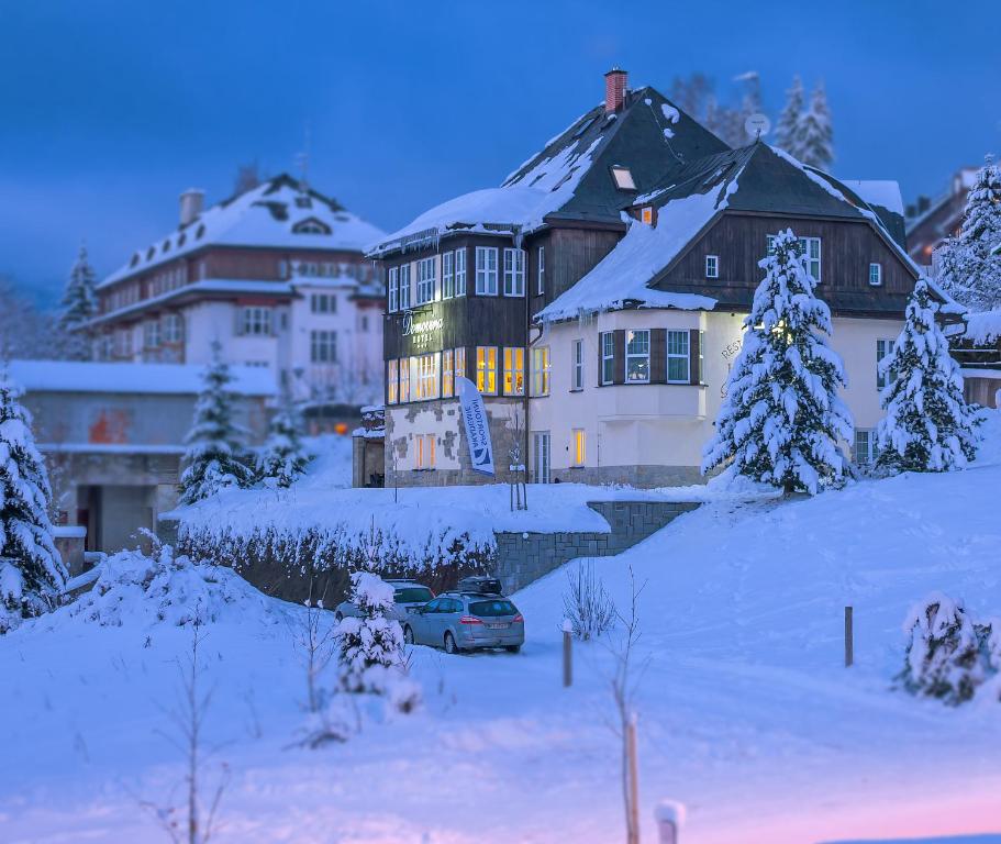 een huis met een auto in de sneeuw bij Hotel Domovina in Špindlerův Mlýn