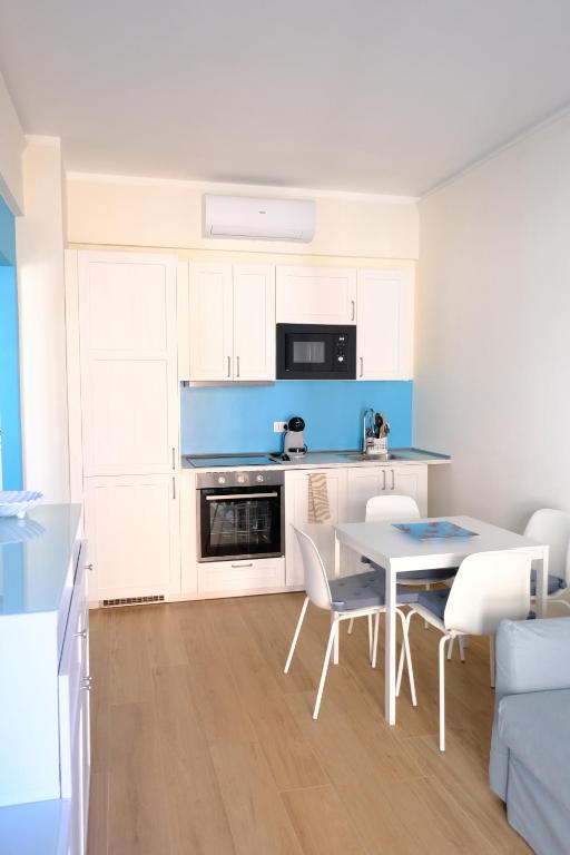 a kitchen with white cabinets and a table and chairs at Perla Blu by PortofinoVacanze in Rapallo
