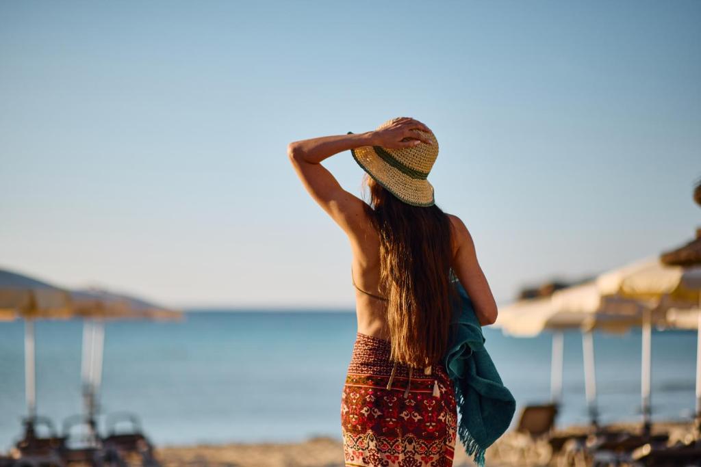 a woman standing on the beach wearing a hat at Nissi Park Hotel in Ayia Napa