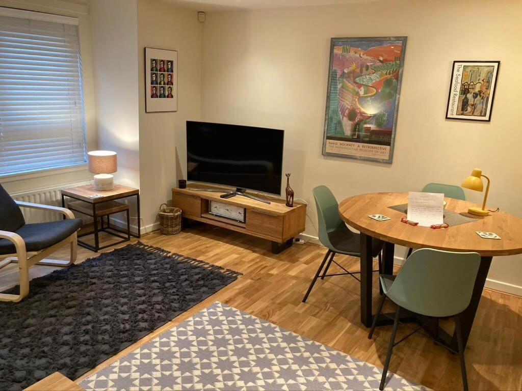 a living room with a table and a television at The Art Flat Woodlands in Glasgow