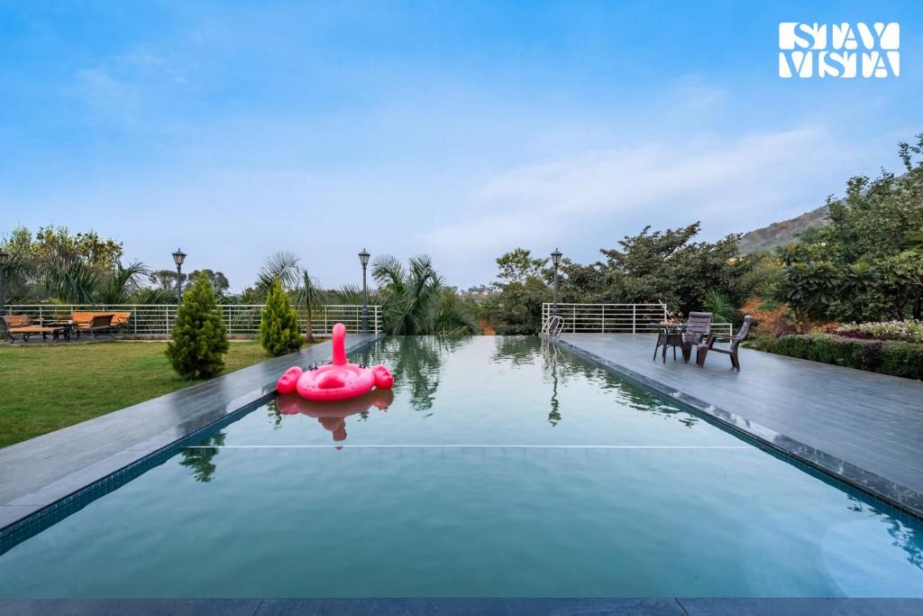 ナーシクにあるStayVista at Banyan Nirvana Villa with Pool, Bonfire & Lawnの空のスイミングプール(水中に浮かぶピンクのボート付)