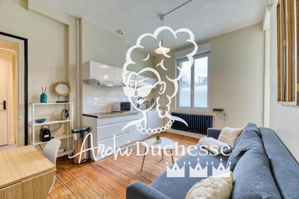 un salon avec un canapé bleu et une cuisine dans l'établissement L'Oiseau Blanc un petit nid proche de la gare !, à Rouen