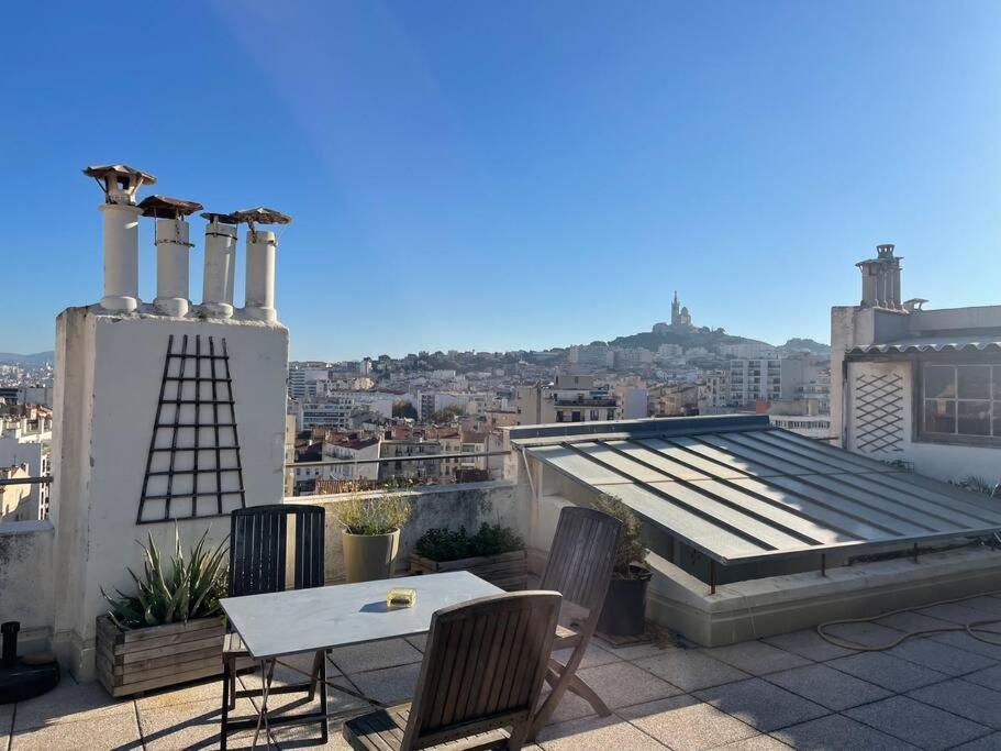 un patio avec une table et des chaises sur un toit dans l'établissement Appartement entre Endoume et Samatan, à Marseille