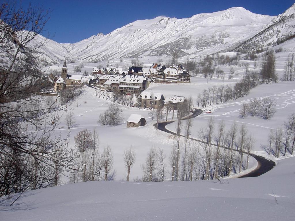 un pueblo en la nieve con una montaña cubierta de nieve en Hostal y Apartamento Seixes, en Bagergue