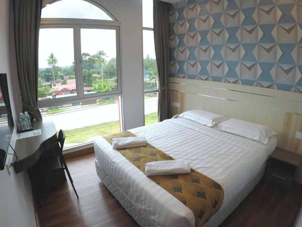 a bedroom with a bed and a large window at HOTEL KAWAN BIDOR in Sungkai
