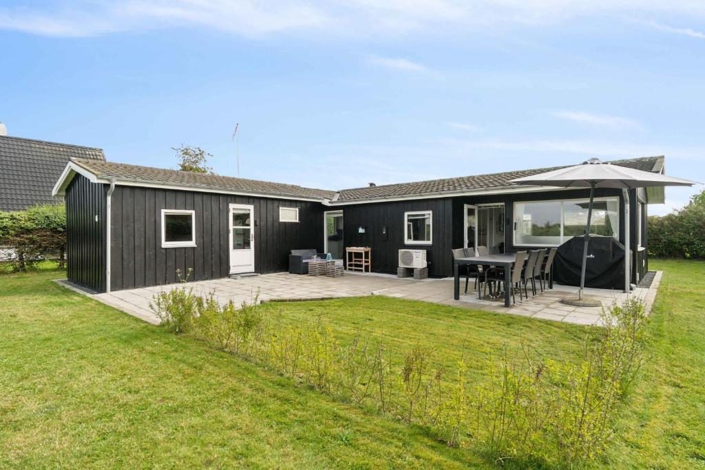 a black house with a deck and a patio at Lovely Summer House In Øster Hurup in Hadsund