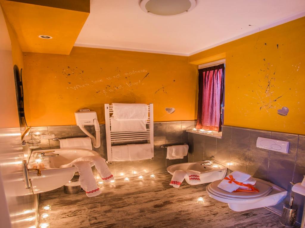 a yellow bathroom with two sinks and a toilet at Hotel Butterfly in Torre del Lago Puccini