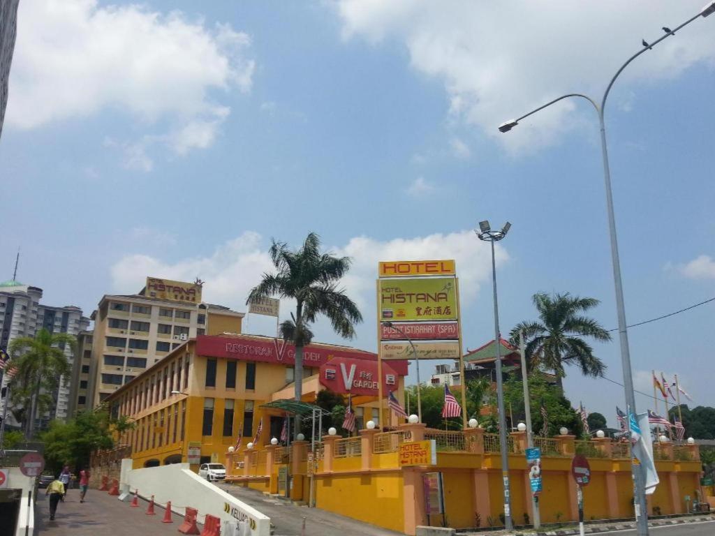 a city street with a yellow building and palm trees at Klang Histana Hotel in Klang