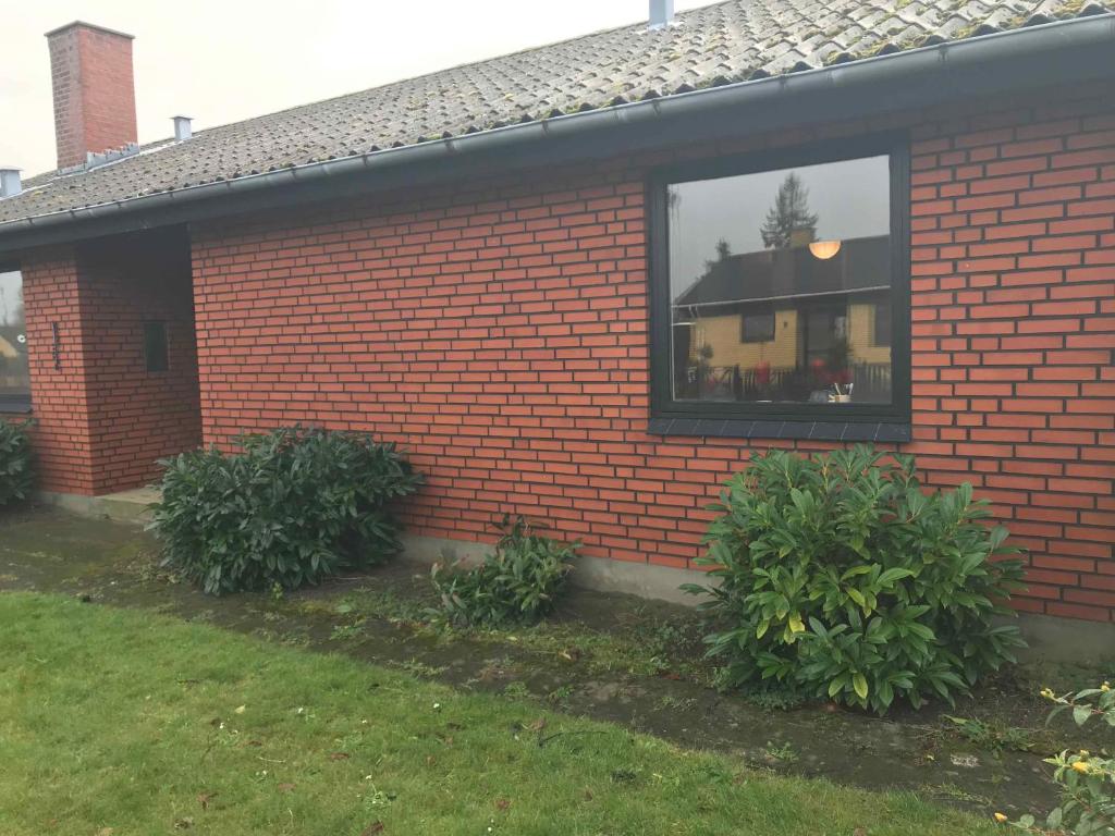 a brick house with two bushes in front of a window at Lovely Holiday Home On Lolland in Errindlev