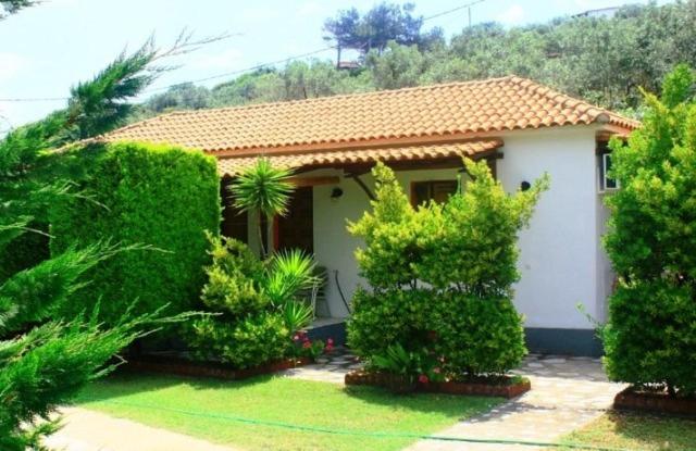 una pequeña casa con árboles y arbustos delante de ella en The Garden, en Potistika