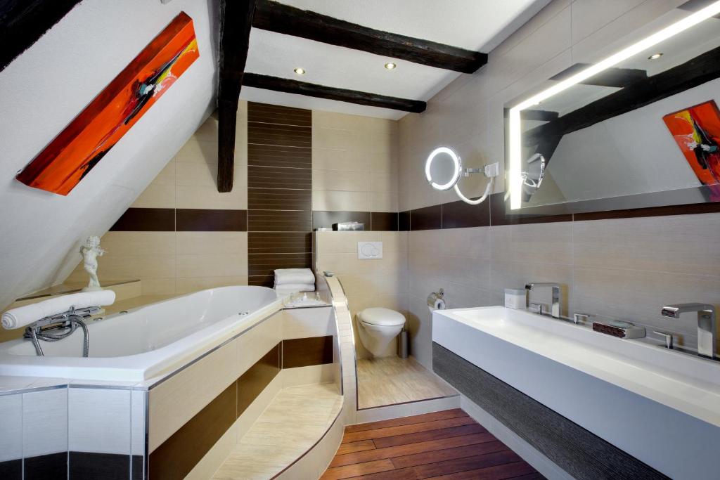 a bathroom with a tub and a sink and a toilet at Hotel Restaurant Le Maréchal - Teritoria in Colmar