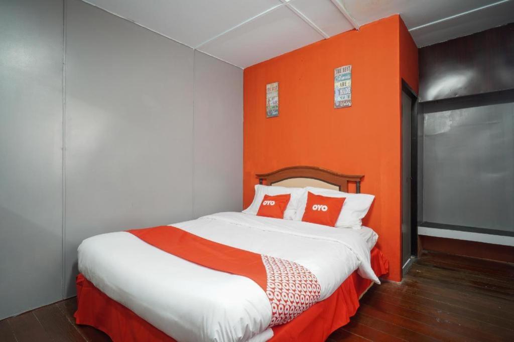 a bedroom with a bed with an orange wall at OYO 89646 Panvill Resort in Pasir Bogak