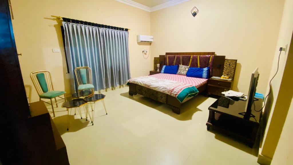 ein Schlafzimmer mit einem Bett und zwei Stühlen und einem Fernseher in der Unterkunft Hyderabad bungalow in Hyderabad