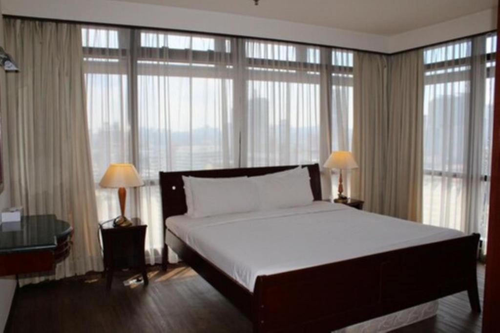 a bedroom with a large bed and large windows at Ridge Service Suites in Kuala Lumpur