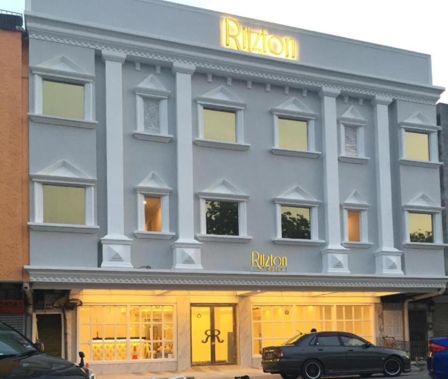 Un edificio gris con una señal amarilla. en Ritzton Hotel, en Johor Bahru
