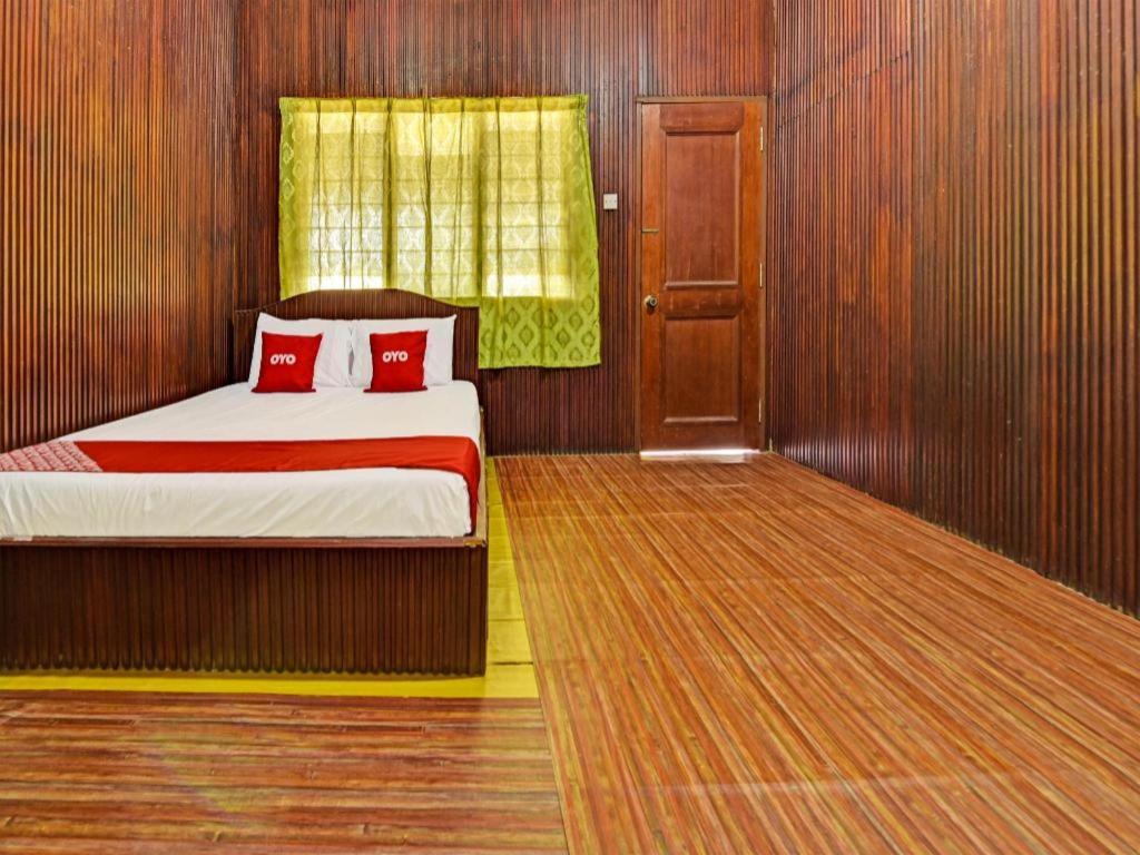 a bedroom with a bed with two red pillows at OYO 90278 Redzwan's Beach Resort in Kota Bharu