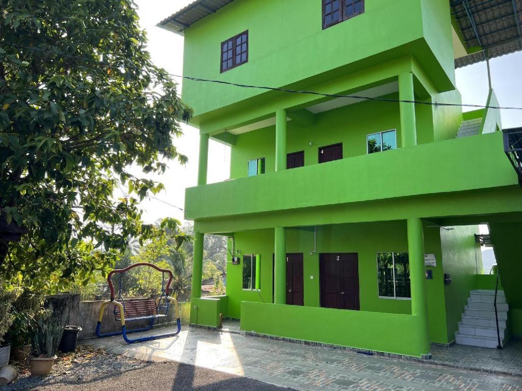 a green building with a bench in front of it at OYO 90462 Padang Besar Green Inn in Padang Besar